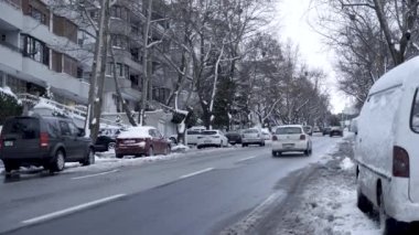 Karlı havada arabalar yokuş yukarı gidiyor.