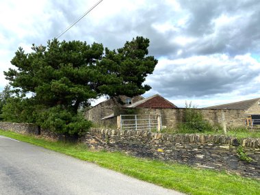 Ek binaları olan bir çiftlik, kuru bir taş duvar ve bulutlu bir gökyüzü, Lower Wyke Lane, Bradford, İngiltere