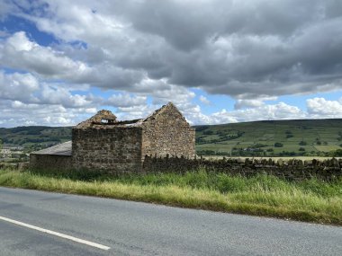 Yol kenarında eski bir taş harabe, kuru bir taş duvar, ve uzak bir alanda, Lothersdale, Keighley, İngiltere