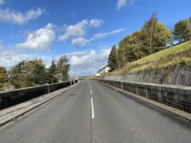 Hebden Yolu boyunca, ağaçlarla ve Haworth, Keighley, İngiltere yakınlarında mavi bir sonbahar gökyüzü.