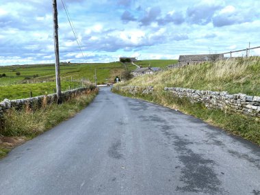 Oxenhope, Keighley, İngiltere 'deki kuru taş duvarlar ve uzak tepeler boyunca Sawood Lane' e bakın.