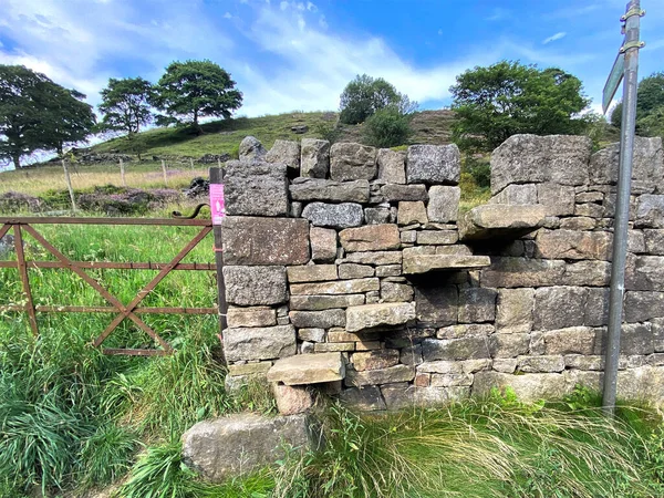 Halifax, Yorkshire, İngiltere yakınlarındaki bir köy yolunda, kuru taş bir duvarın üzerinde eski taş basamaklar.