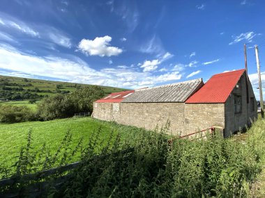Nebiggin, Leyburn, İngiltere 'deki tepeleri ve tarlaları olan, Straight Head Bank yolunda kısmen kırmızı çatılı bir bina.