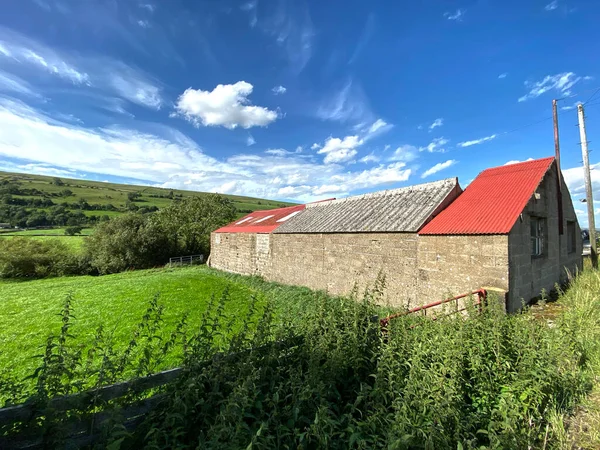 Nebiggin, Leyburn, İngiltere 'deki tepeleri ve tarlaları olan, Straight Head Bank yolunda kısmen kırmızı çatılı bir bina.
