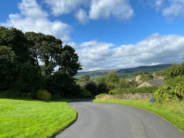 Yol, Draughton köyüne gidiyor, uzak mesafelerde tarlaları ve tepeleri var.