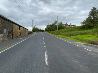 Karanlık ve bulutlu bir günde, Denshaw, Oldham, İngiltere 'de evleri ve ağaçları olan Ripponden Yolu' nu izleyin.
