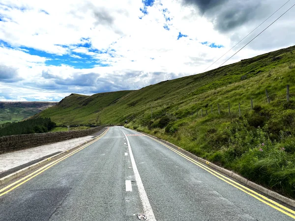 Huddersfield Yolu 'nun tepesinde, Greenfield rezervuarının yakınındaki orman, ağaçlar ve yabani bitkilerle Oldham, Lancashire, İngiltere
