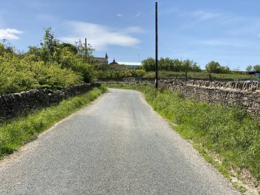 Derin Lane 'e bakıyorum, kuru taş duvarlar, çimen kenarları ve Bradford, Yorkshire, İngiltere yakınlarında bir kulübe.
