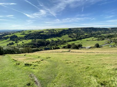 Halifax, Yorkshire, İngiltere yakınlarındaki güneşli bir günde, uzaktaki tarlaları, vadileri, ağaçları ve tepeleri olan Howes Lane 'den manzara.