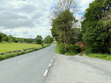 B6265 Skipton 'dan Grassington yoluna bakıyoruz. Tarlaları, ağaçları ve küçük bir taş kalıntısı var. Skipton, Yorkshire, İngiltere.