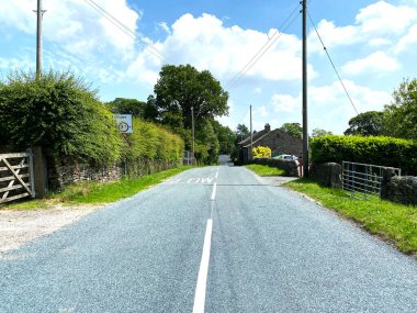 Kildwick köyüne giden yol, çalılar, ağaçlar ve yakınlardaki kulübelerle, Kildwick, Keighley, İngiltere 