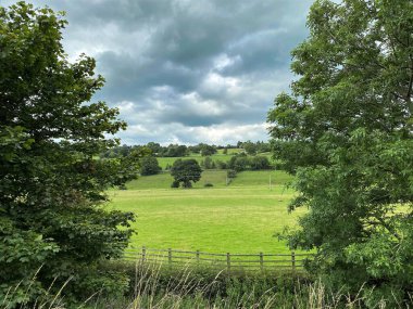 Airedale Vadisi 'nin karşısındaki çayırlara, ağaçlara ve Keighley, Yorkshire, İngiltere yakınlarındaki ağır bulutlara bakın.