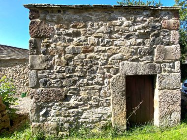 Stirton Lane, Skipton, İngiltere 'de çok alçak kapılı, çimenli ve parlak mavi gökyüzü olan küçük eski taş bina.