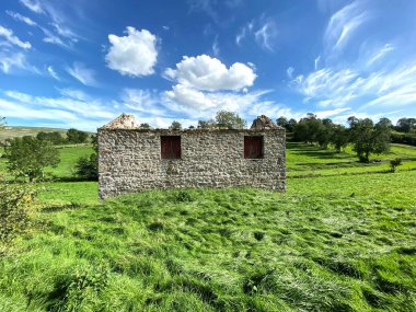 Old stone barn without a roof, with boarded up windows, in a large field, by the B6160 in, Burton cum Walden, Leyburn, UK