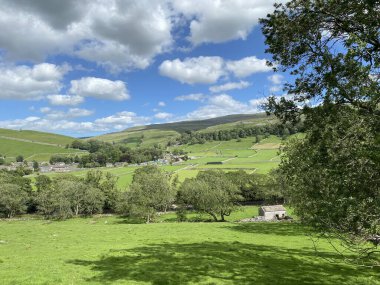Çevresindeki tarlalar, ağaçlar, çiftlik evleri ve tepelerle Kettlewell, Skipton, İngiltere