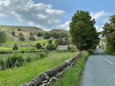 Kilnsey köyü, küçük bir gölü, ağaçları, evleri ve tepeleri var.