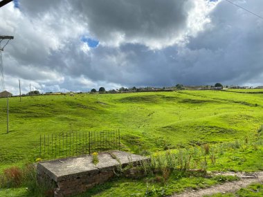 Denholme kırsalında şiddetli fırtına bulutları, yeşil bir tepe, çiftlik ve evler