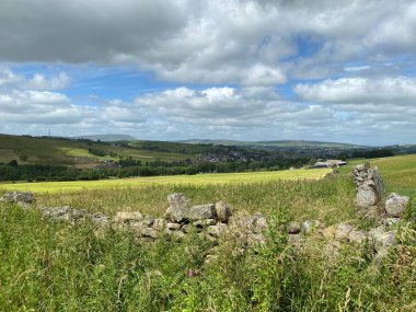 Kuru bir taş duvarın üzerinden bakıyorum, tarlaları, çayırları ve yakınlardaki bir köyü, Trawden, Colne, İngiltere.