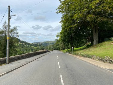Cragg road, leading down to Hebden Bridge, with dry stone walls, trees, and a farm house in, Hebden Bridge, Halifax, UK