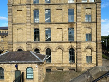 Large stone built, Victorian former textile mill, with the original police building preserved for history in, Saltaire, Bradford, UK