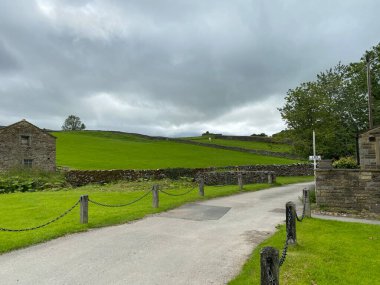Old barn, next to a house, with a road, fencing, and heavy rain clouds near, Gargrave, Skipton, UK