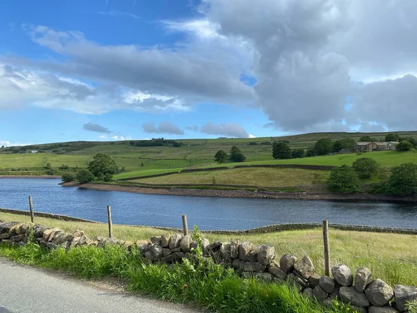 Stanbury reservoir, with a dry stone wall, and broken cloud in, Haworth, Keighley, UK