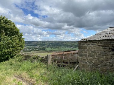 Old farm machinery, and a derelict stone building, with a view toward Crosshills, Keighley, UK