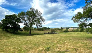 Bulutlu bir günde öğleden sonra, tarlalar, ağaçlar ve uzak çiftliklerle birlikte, İngiltere 'nin Bradford, Tong köyünün yakınlarında.