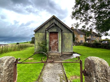 Thorlby, Skipton, İngiltere 'de bulutlu ve nemli bir günde eski yeşil boyalı metal bir bina.