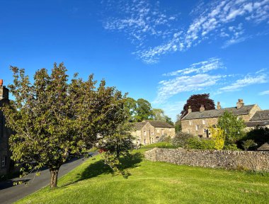Yorkshire Dales village of Airton, with old cottages, dry stone walls, trees, and a blue sky in, Airton, Skipton, UK