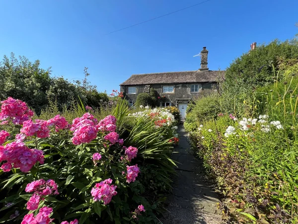 An English country garden, with flowers, bushes, and an old cottage near, Holm Lane, Austwick, UK