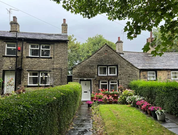 Old stone cottages, with hedges, trees, and garden flowers, on a rainy day, in the post industrial city of, Bradford, UK