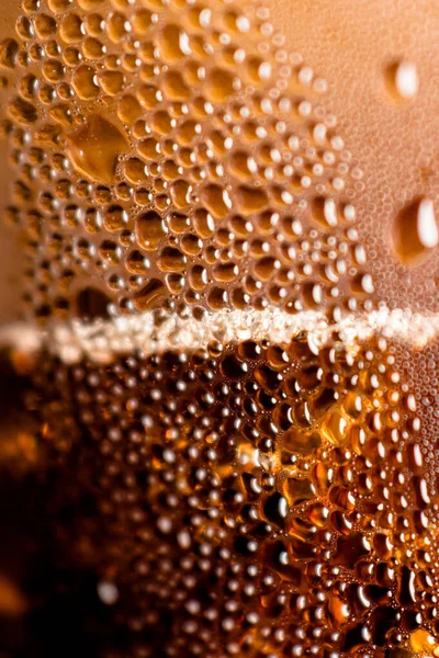 drops of condensate on a cold glass glass with brown carbonated drink