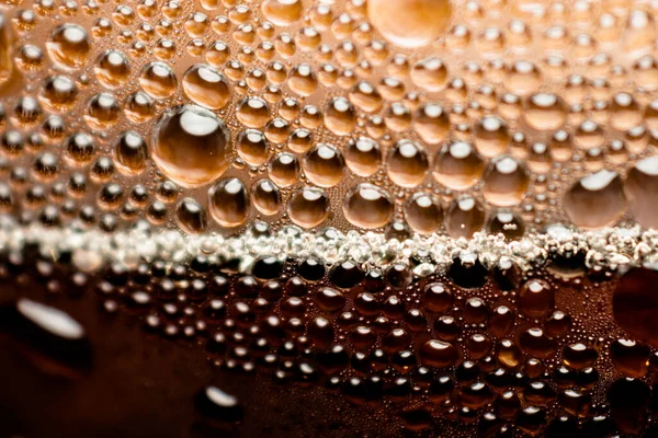 drops of condensate on a cold glass glass with brown carbonated drink