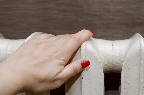 warming hand on heating radiator. Heating of a residential building in winter.