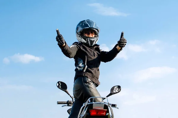 骑摩托车与蓝天作对的女人竖起大拇指 因为发生了件好事 — 图库照片