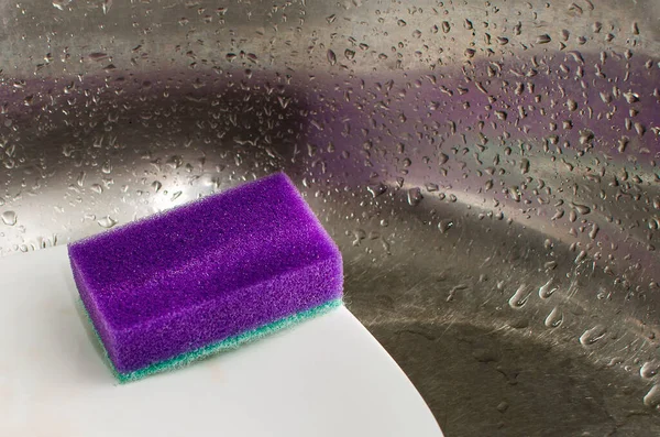 sponges and dish washing liquid soap on dirty sink.