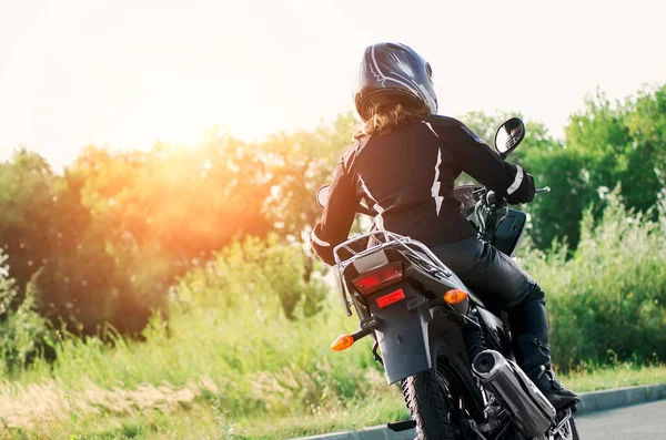 在皮革夹克和一辆摩托车头盔骑自行车的女孩 — 图库照片