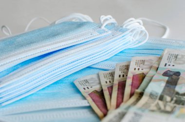 Paralı tıbbi maske yığını. Tıbbi maske ve para. Cerrahi maske. COVID-19 yüz maskesi sıkıntısına neden oldu. Tıbbi maske ve Rus banknotları.