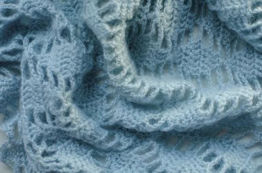 Fragment of a knitted woolen plaid close-up. blue threads, large knitting pattern, all the loops are visible.