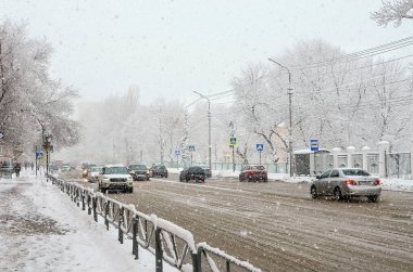 Saratov, Rusya... 18 Aralık 2021: Karlı bir cadde boyunca bir sürü araba sürüyor. Kötü hava, kar fırtınası.