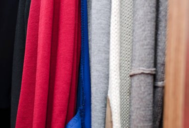 Örgü giysiler dolaptaki askılara asılır. Yakın çekim, seçici odaklanma.