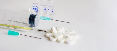 İlaç tedavisi, aşı konsepti. Termometre, aşı şişeleri, enjeksiyon, şırınga, beyaz arka planda haplar. Yatay fotoğraf. Metin ve metin boşluğu için yer.