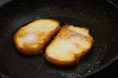 Yumurtada kızartılmış tost ve üzerine şeker serpiştirilmiş, yakın plan.