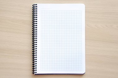 Tarafsız arka planda okul not defteri, ahşap masada spiral not defteri