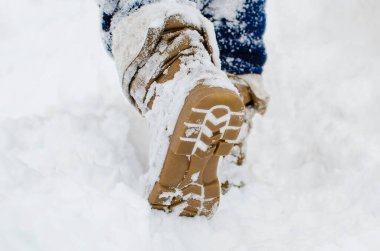 Kahverengi çizmeli bir adam karlı bir yolda yürüyor. Yakın çekim, seçici odaklanma.
