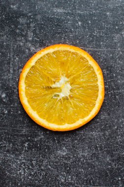 Siyah renkli arka planda portakal dilimi. Dikey fotoğrafçılık.