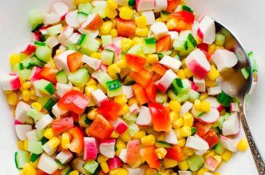 Salatalık salatası, mısır, dolmalık biber ve yengeç çubukları beyaz kasede. Yakın plan..