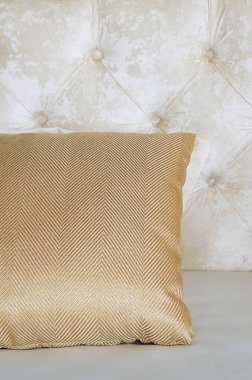 Yatağın üzerindeki bej yastığı kapat. Dikey fotoğrafçılık.