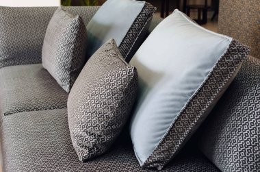 Beyaz ve gri dekoratif yastıklar. Oturma odasındaki gündelik bir kanepede desenli. Yakın çekim, seçici odaklanma.